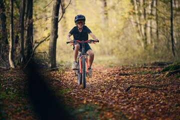 Enfant en v&eacute;lo dans les bois en automne