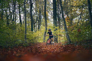 Enfant en v&eacute;lo dans les bois en automne
