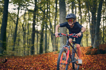 Enfant en vélo dans les bois en automne