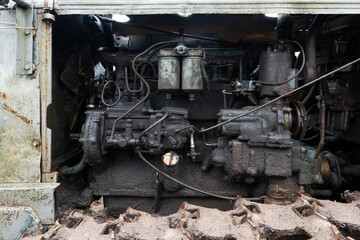 Close-up of the engine compartment of a vintage caterpillar tractor. Old parts are covered with a thick layer of dirt. Background