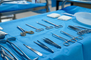 surgical instruments and tools including scalpels, forceps and tweezers arranged on a table for a surgery, Sterilized surgical instruments on the blue wrap
