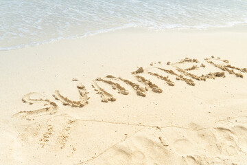 Close-up Of Summer Text Written On Sandy Beach Near The Seashore.  Beach and sea.