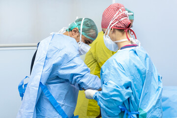 nurse in operating room dressing surgeon in pre-operative gown and gloves