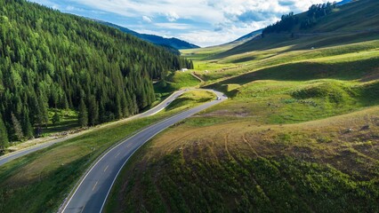 Aerial view of a winding road surrounded by greenery on a sunny day