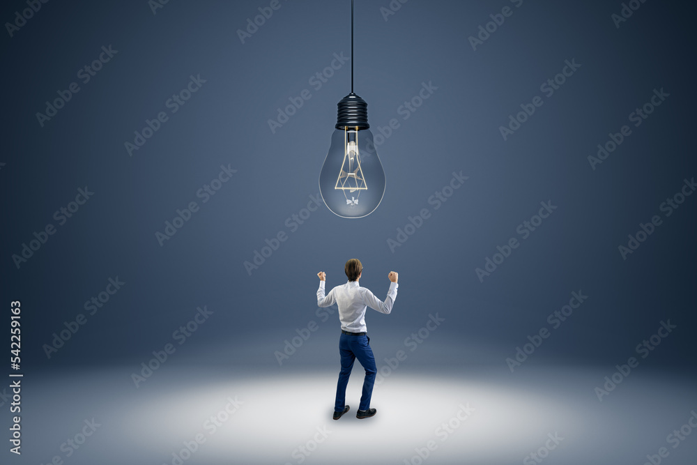 Poster back view of young businessman with abstract huge lamp hanging above. idea, innovation and brainstor
