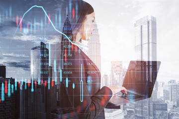 european businesswoman using laptop with creative candlestick forex chart index hologram on blurry background. Trade, business market and finance analysis concept. Double exposure.