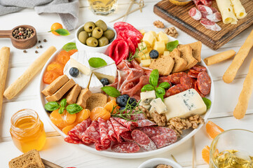 Charcuterie board with a variety of cheeses, salami, chorizzo, prosciutto, honey, grapes, nuts,...