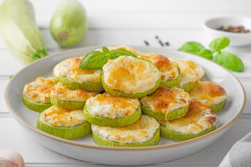 Baked zucchini with cheese, garlic and fresh herbs on a white wooden background. Selective focus