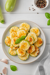 Baked zucchini with cheese, garlic and fresh herbs on a white wooden background. Selective focus