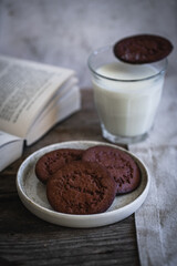  Norwegian Christmas spiced cookies pepperkaker with glass of milk and open book on wooden table .