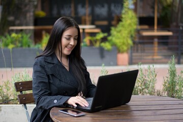 Beautiful woman working on a laptop at an outside cafe
