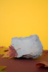 Podium made of stone on an orange background with autumn leaves, space for text, free space