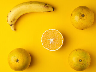 Oranges and bananas on a table with a yellow background.