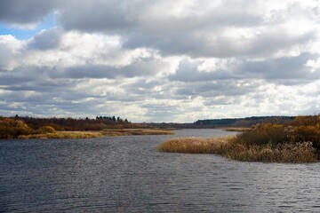 Autumn colors. Sky and clouds on a windy day at the lake. Thickets of reeds along the banks.