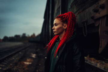 Portrait of a beautiful woman with red hair and dreadlocks at the railway station