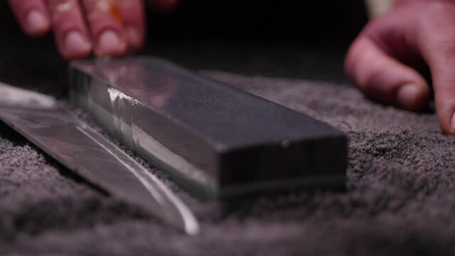 Hands sharpening a knife with a stone