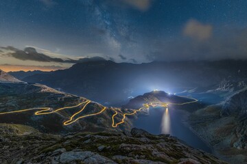 Obraz premium Mystic view of a lake and mountains on a starry night in the Gran Paradiso, Colle del Nivolet, Italy