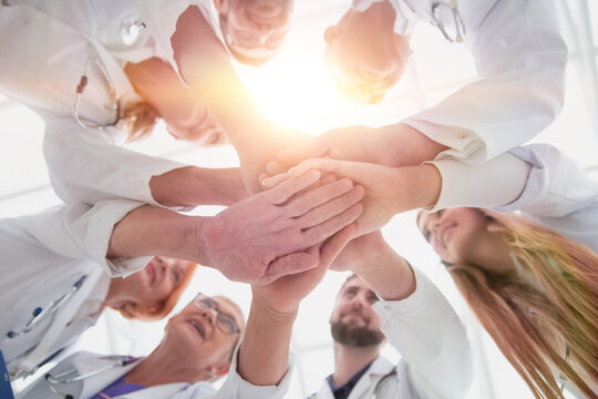 close up. group of different doctors putting their hands together