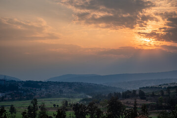 Naklejka na ściany i meble A view of the sun setting over the hills in Kigali, Rwanda