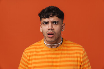 Fototapeta premium Brunette young man wearing t-shirt expressing surprise at camera