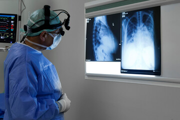 unknown doctor examining patient x-rays in operating room with magnifying glasses