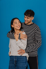 Young smiling stylish guy hugging his happy beautiful asian girlfriend