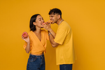 Naklejka premium Young asian woman and man eating donuts with closed eyes