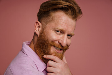 Fototapeta premium Adult handsome stylish redhead bearded smiling man touching his chin