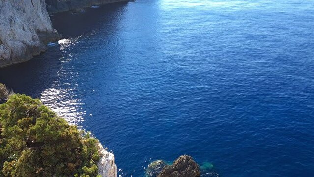 A tilting upward shot of a lighthouse built on a cliff top at the cape of an island.