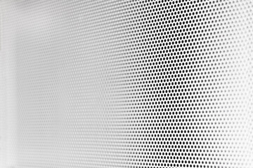 White grill texture with little circular holes with degraded focus in perspective to the left side