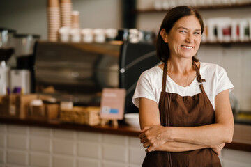 White mature barista woman smiling while working in cafe