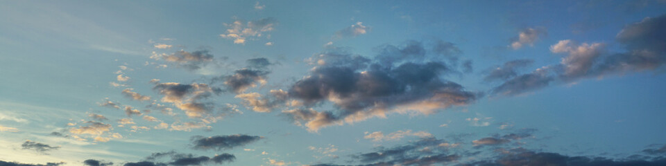 Panoramic view of cloudy blue heaven at sunset. Dramatic sunny sky in evening time.