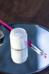 White acrylic powder to strengthen the nail plate and a brush in the reflection of the mirror