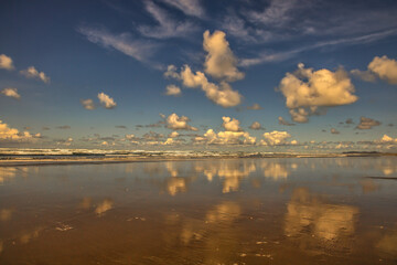 clouds reflected on wet sand at sunrise