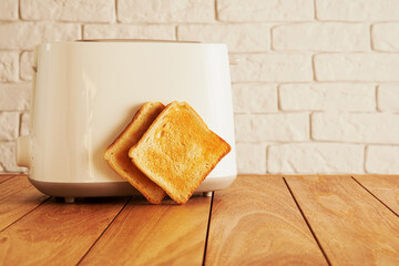 White electric toaster and toasted bread slices on the modern kitchen. Cooking and homeware technologies backgrounds - obrazy, fototapety, plakaty
