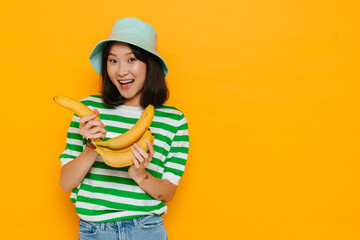 Asian young woman wearing panama smiling while holding bananas