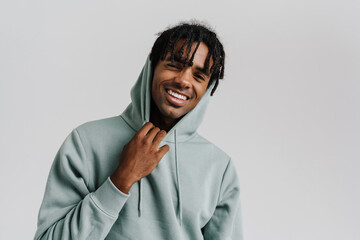 Young african man in hood smiling while standing isolated