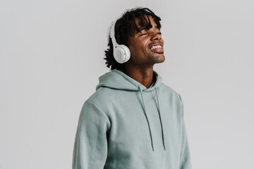 Young man smiling while listening music with headphones isolated