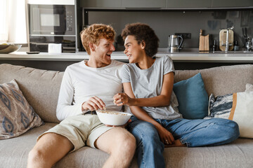 Young beautiful happy interracial couple eating popcorn and looking