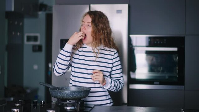 Woman eats unhealthy fried food from a pan, suffers from severe stomach ache at kitchen. Female tries roasted snack then feels extremely sick. Girl suffering from a sharp gastritis, ulcer liver pain.