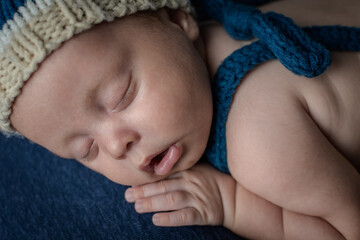 Cute newborn baby dressed in suspender shorts and tassel cap