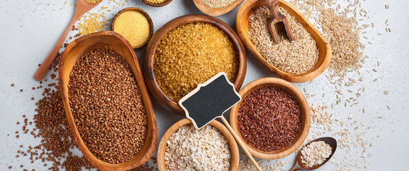 Variety of grains. Assorted cereals white, brown and red rice, buckwheat, millet, corn groats, quinoa and bulgur in wooden bowls.  Food supply crisis. Global food crisis. Top view. Copy space. Banner