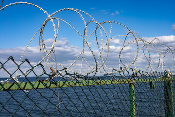 Barbed wire on the fence. Sea view
