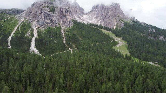 Aerial flight over larch trees in the beautiful Alps. High mountain peaks with mist after rain, Dolomites, Italy