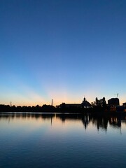 Fototapeta premium beautiful sunset on the shore of the lake with ducks on the background of the city