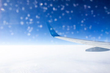 Fototapeta na wymiar Airplane wing in frozen porthole in a plane during the flight. Amazing scenic view through the aircraft window against the blue sea and sky