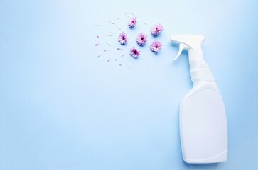 White plastic bottles of room cleaning spray with chrysontems and flower petals lie on a blue background.  The concept of freshness and aroma in rooms.  Space for copy text.  Flat lay, close-up.