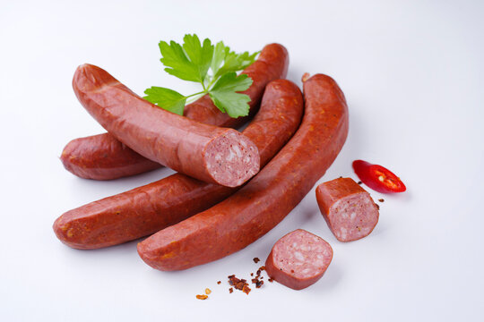 Traditionelle rohe bayrische scharfe Bratwurst mit Chili angeboten als close-up auf wei&szlig;em Board und Petersilie mit Textfreiraum 
