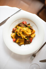 Appetizing Italian pasta with duck meat on a light background. Beautiful serving. Exquisite presentation of food.