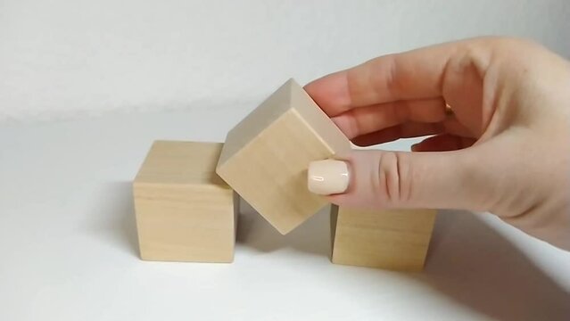 Mathematical count for subtraction 3-1=2 A person dismantles a structure from wooden blocks, removes the blocks manually.